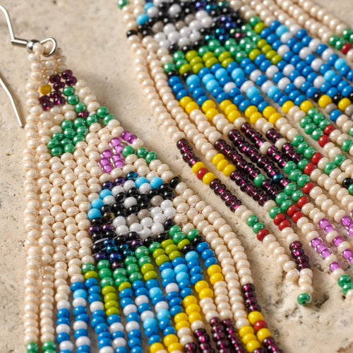 Colorful beaded earrings with a geometric pattern on a textured surface