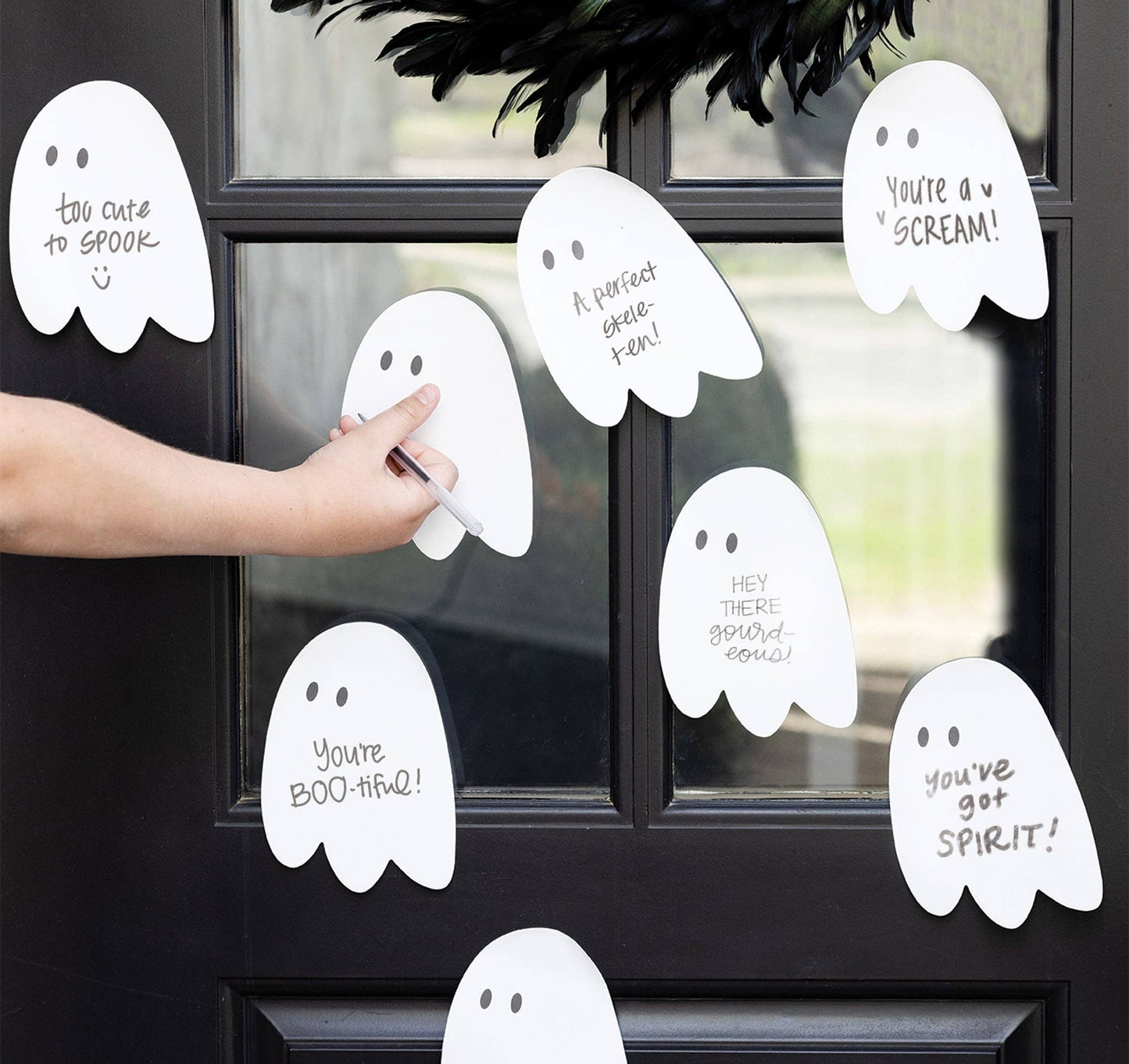 Decorative ghost-shaped window clings with humorous text on a black window.