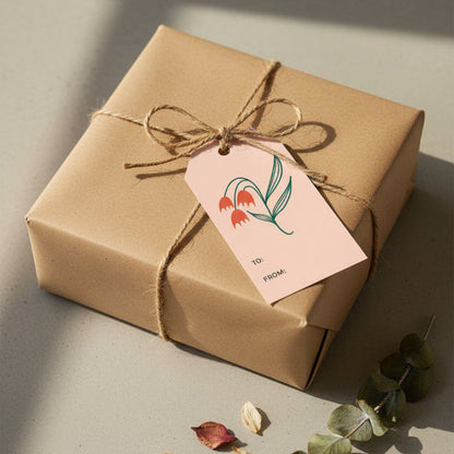 Dosado Red gift tag added to a brown paper wrapped gift with twine and eucalyptus and gray background 