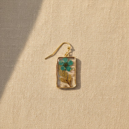 Close-up of botanical turquoise and green leaf details embedded in resin on a textured background