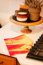 Decorative items including a candle, potted plant, and colorful towel on a surface.