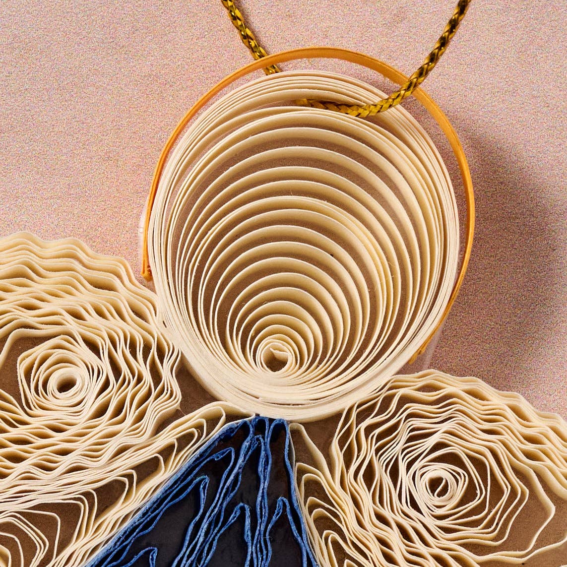 Decorative wall art with rolled paper and blue fabric on a beige background