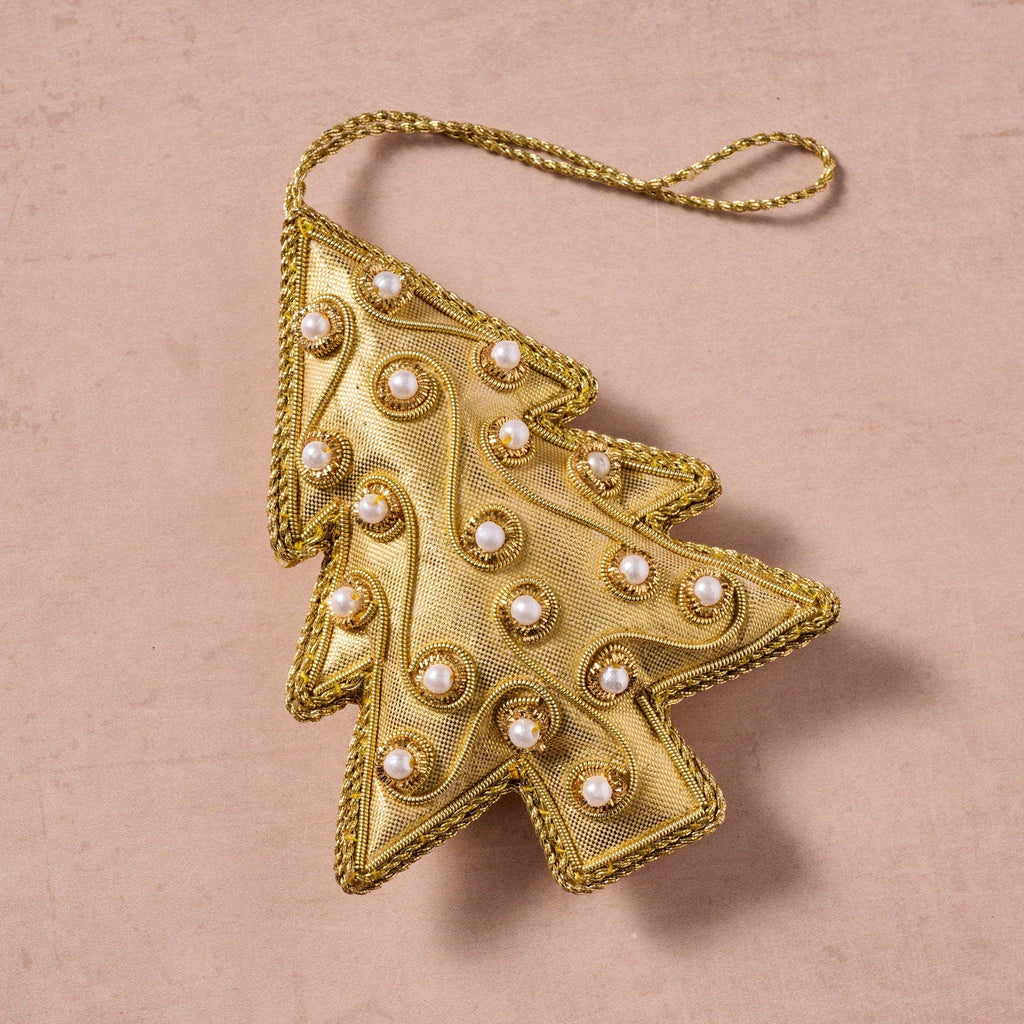 Gold Christmas tree ornament with pearl-like embellishments on a beige background