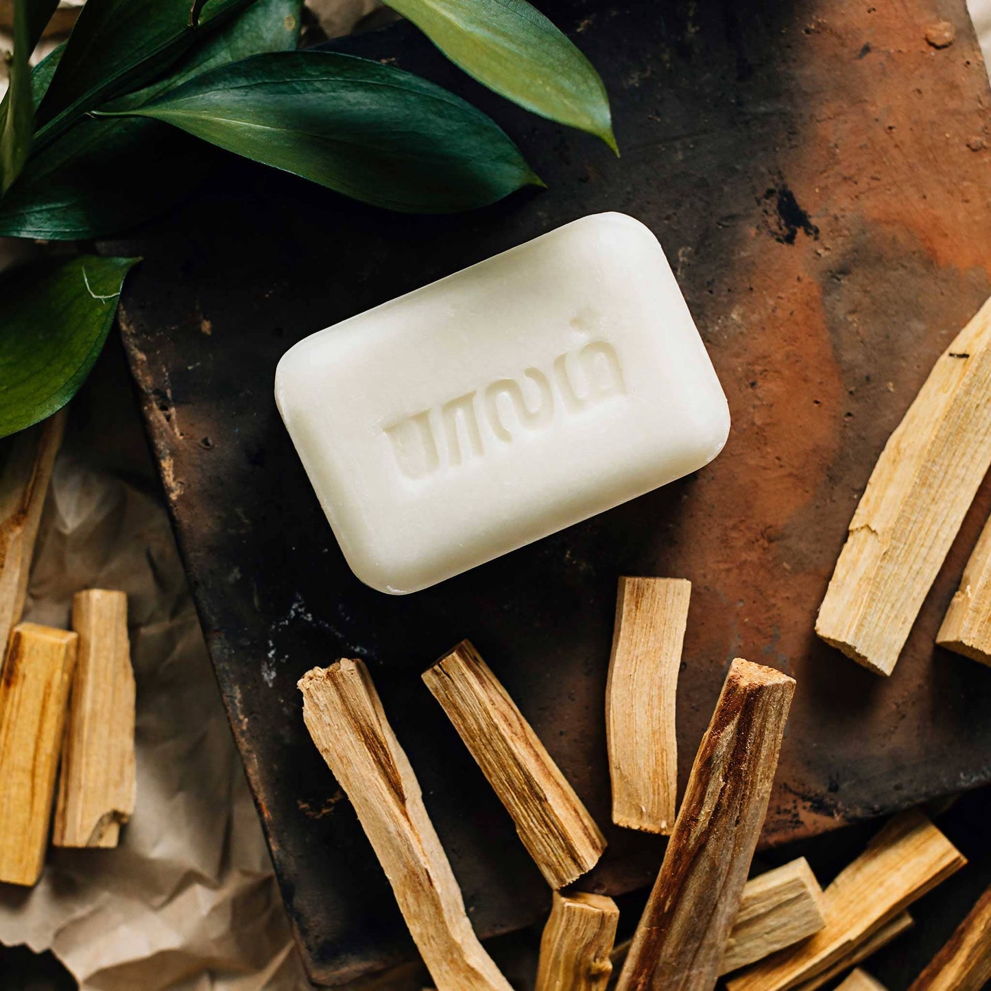Bar of soap with 'Mandara' branding on a rustic surface with wood and leaves.