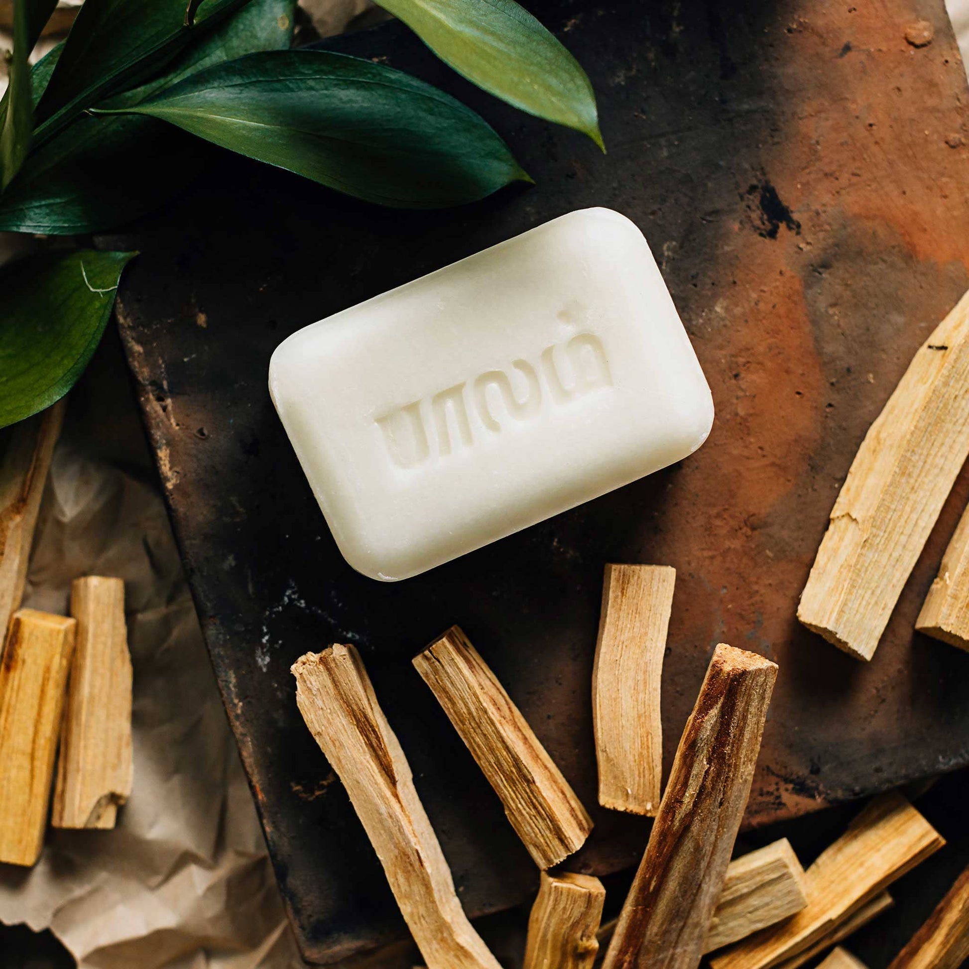 Bar of soap with 'Mandara' branding on a rustic surface with wood and leaves.