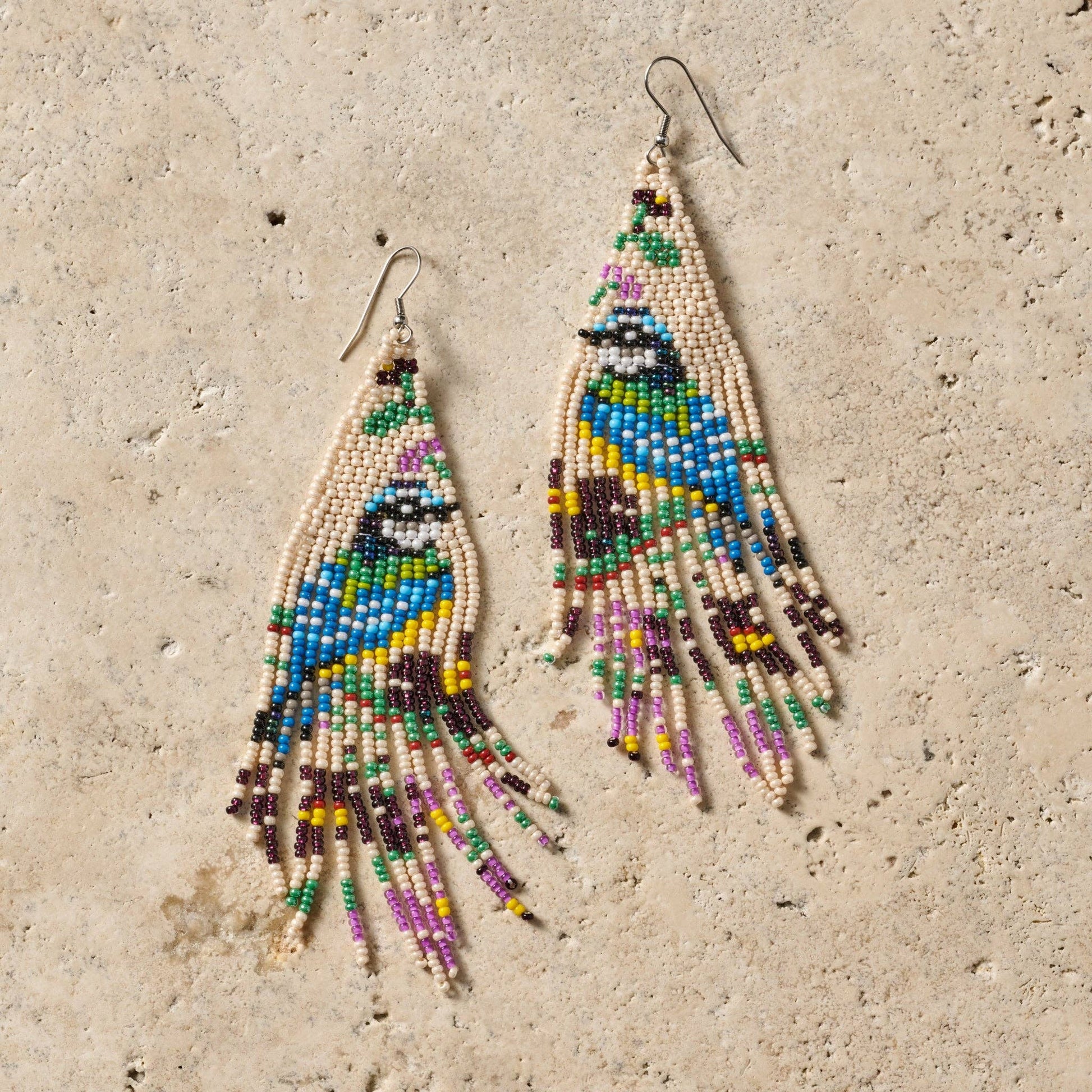 Colorful beaded earrings on a textured beige surface