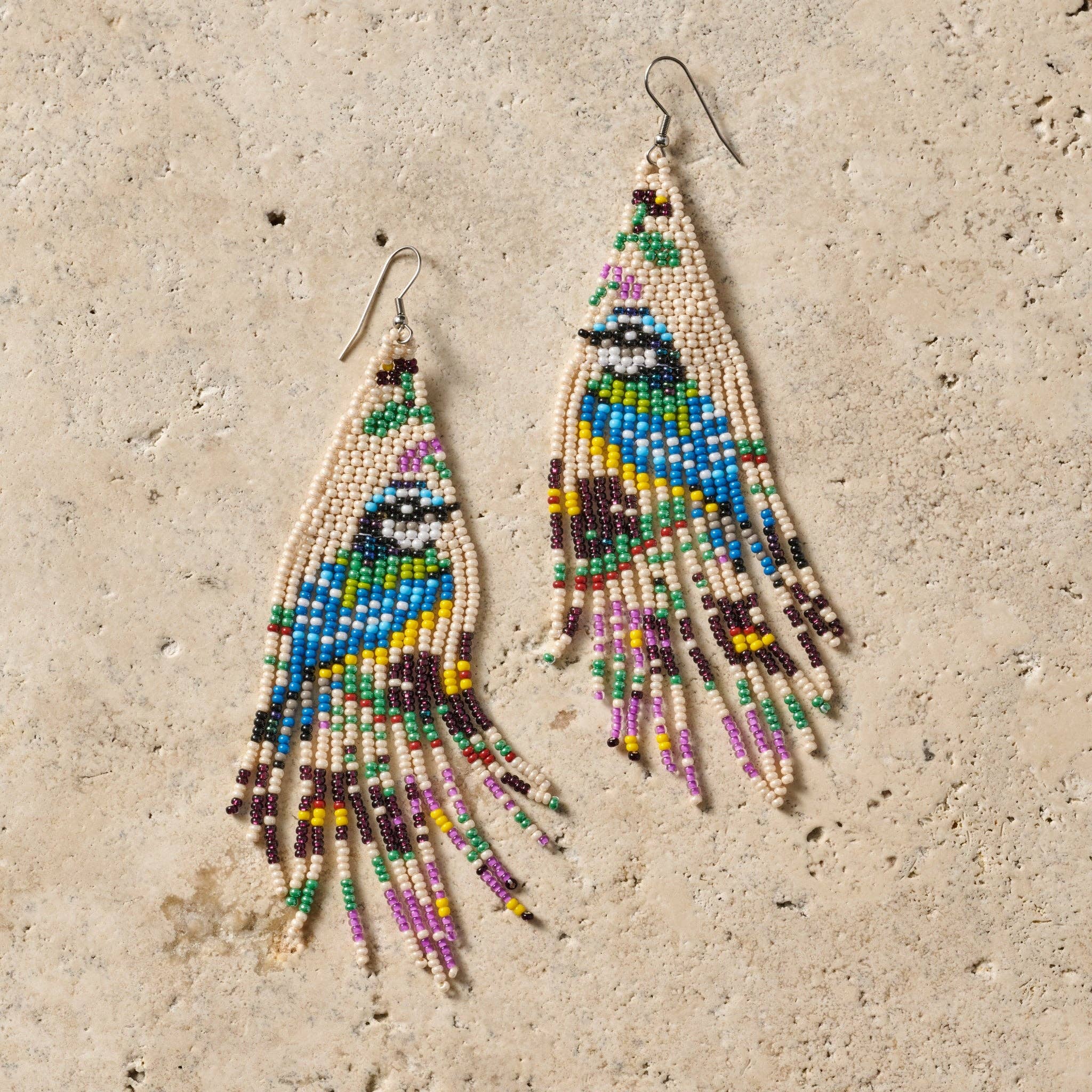 Colorful beaded earrings on a textured beige surface