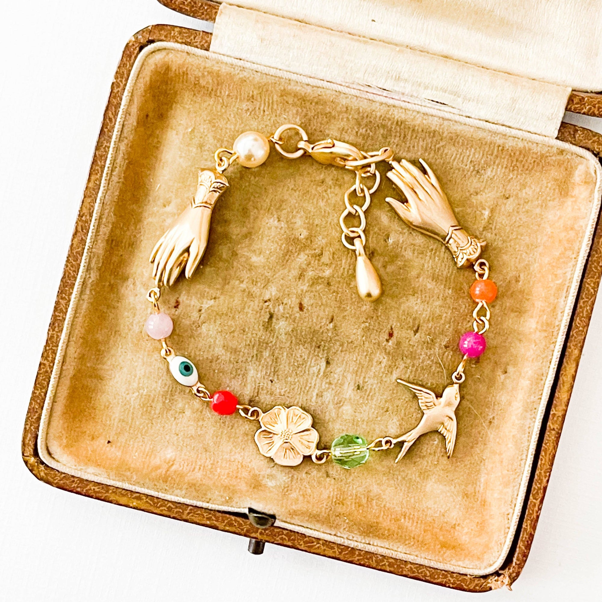 Close-up of coral, pearl, and evil eye charm on handmade bracelet