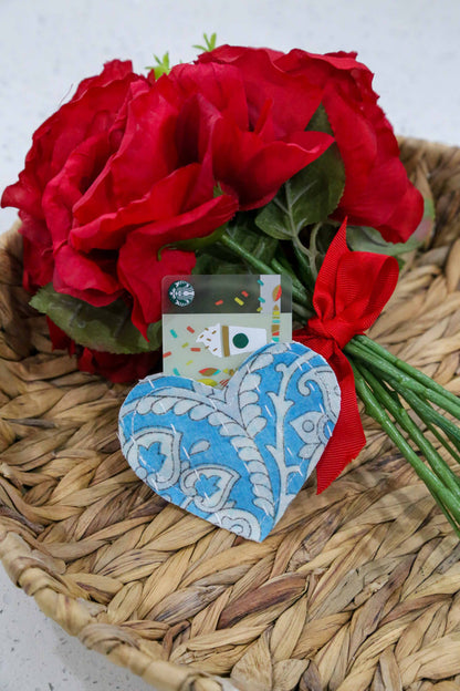 Red roses with a blue heart-shaped card on a woven surface
