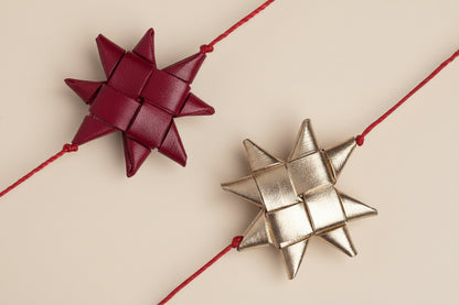Two star-shaped decorative bows, one red and one gold, on a white background.