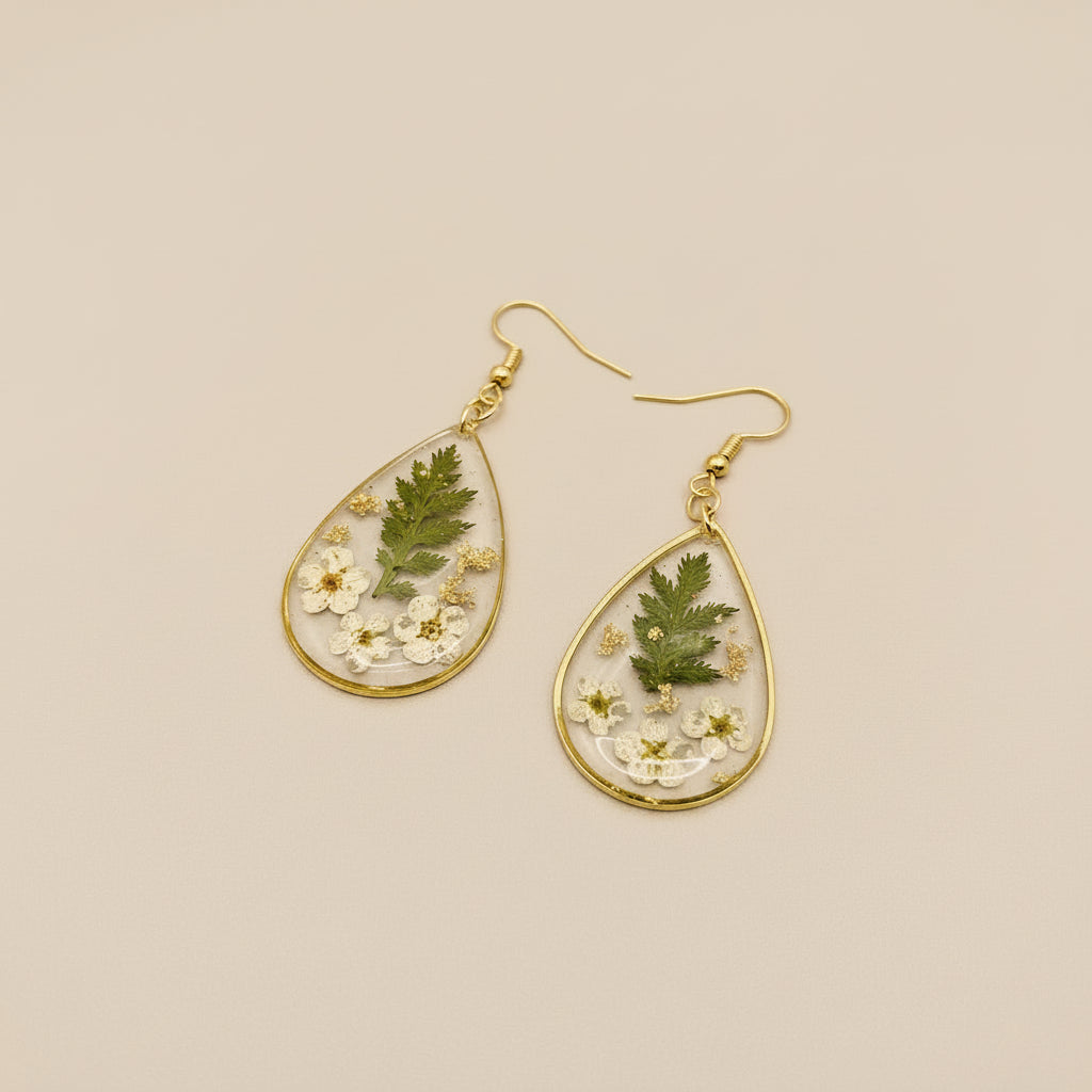 Teardrop-shaped earrings with floral and green leaf designs on a gray background