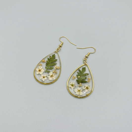 Teardrop-shaped earrings with floral and green leaf designs on a gray background