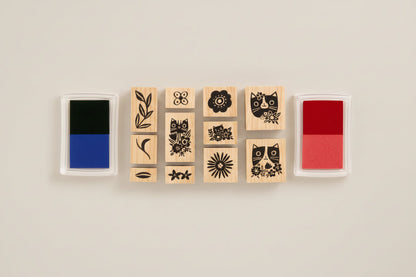 Set of wooden stamps with floral and cat designs, accompanied by ink pads on a white background.