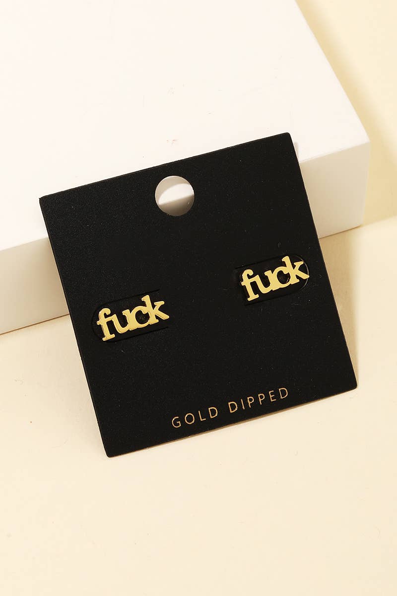 Close-up of gold-dipped “fuck” stud earrings on a velvet earring card