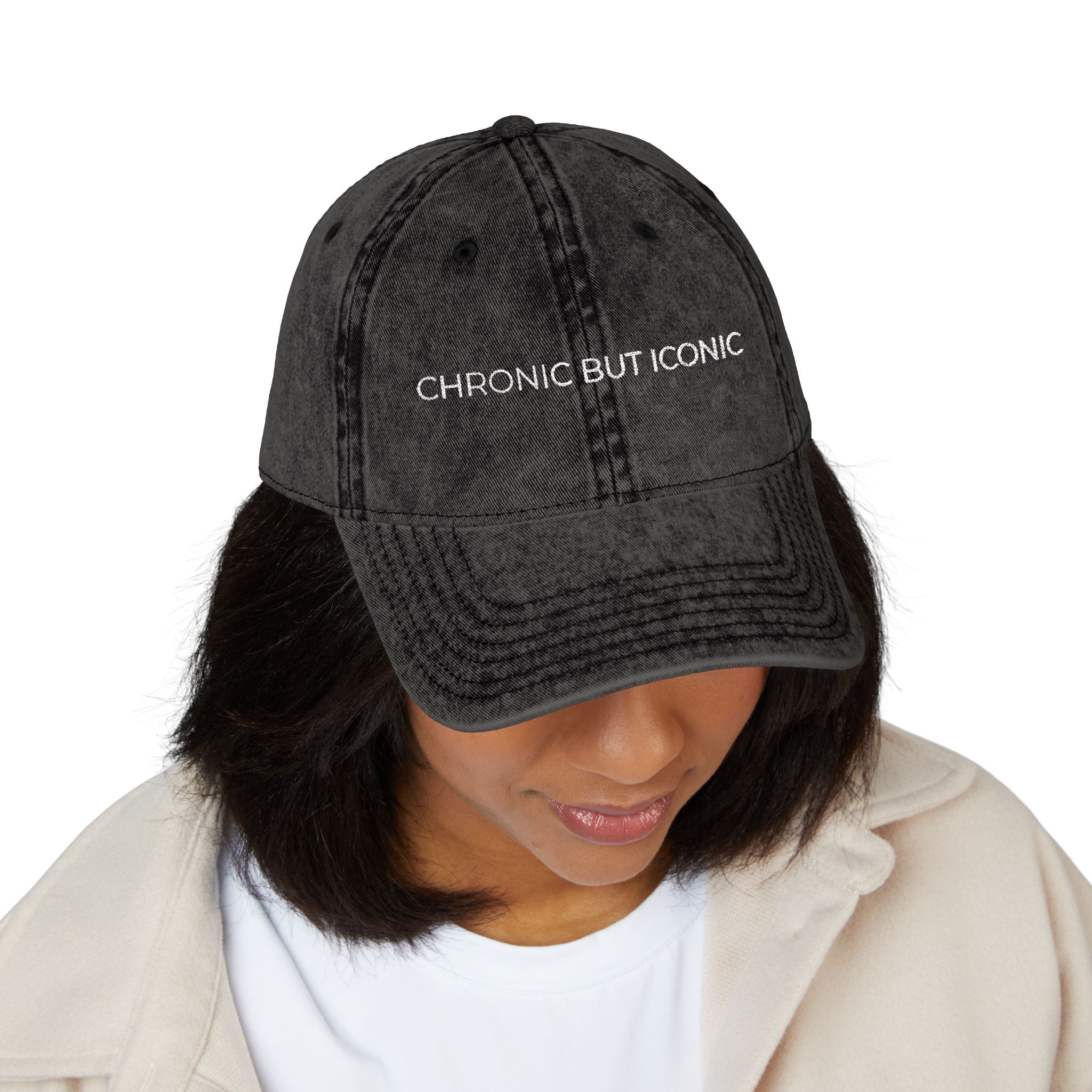 Person wearing a black cap with 'CHRONIC BUT ICONIC' text on a white background
