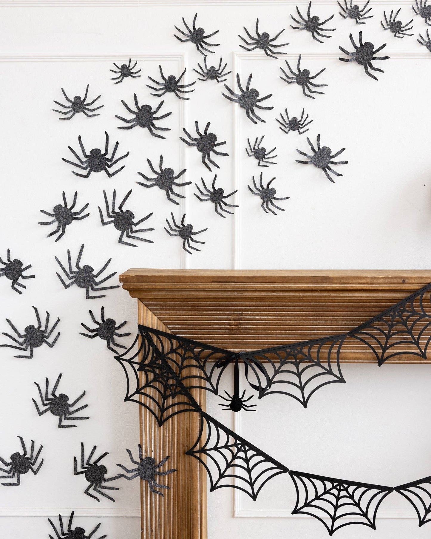 Set of 50 glitter spiders in assorted sizes arranged on a wall in a spooky Halloween display