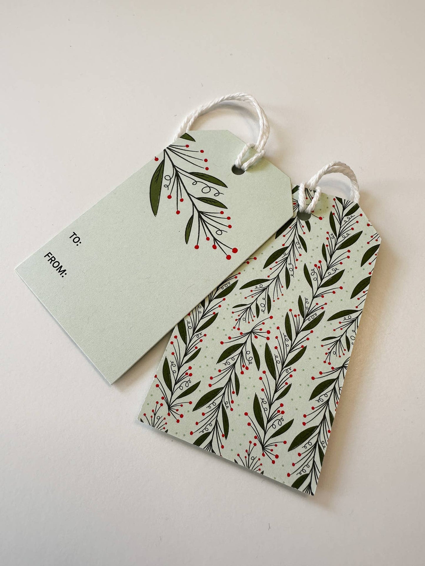 Close-up of mistletoe-themed recycled paper gift tags with red and green details