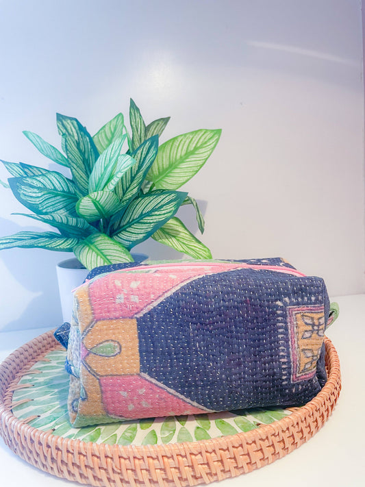 Colorful patterned zipper box pouch on a woven tray with a plant in the background