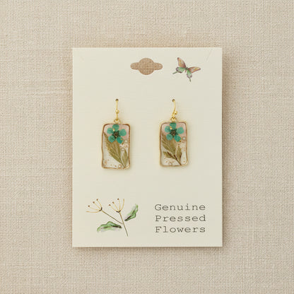Pair of earrings with pressed flowers on a card labeled 'Genuine Pressed Flowers'