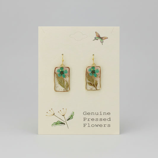 Pair of earrings with pressed flowers on a card labeled 'Genuine Pressed Flowers'.