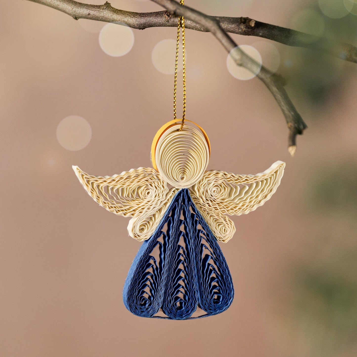 Decorative angel ornament with gold wings and blue body hanging from a branch.