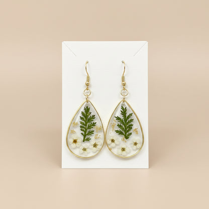 Teardrop-shaped earrings with floral and leaf designs on a paper earring back.