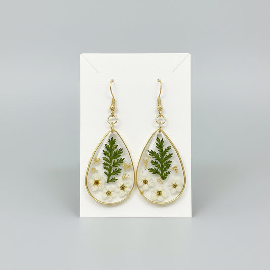 Teardrop-shaped earrings with floral and leaf designs on a paper earring back.