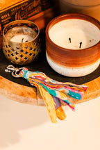 Ceramic candle with decorative keychain on a wooden surface