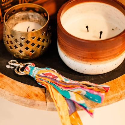 Ceramic candle with decorative keychain on a wooden surface