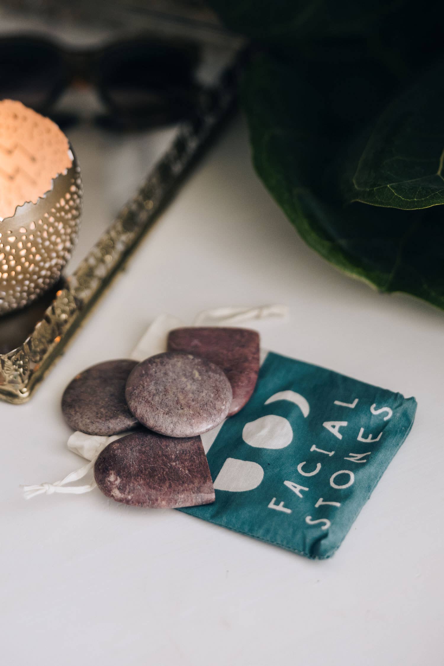 Facial stones and a green pouch labeled 'Facial Stones' on a white surface.