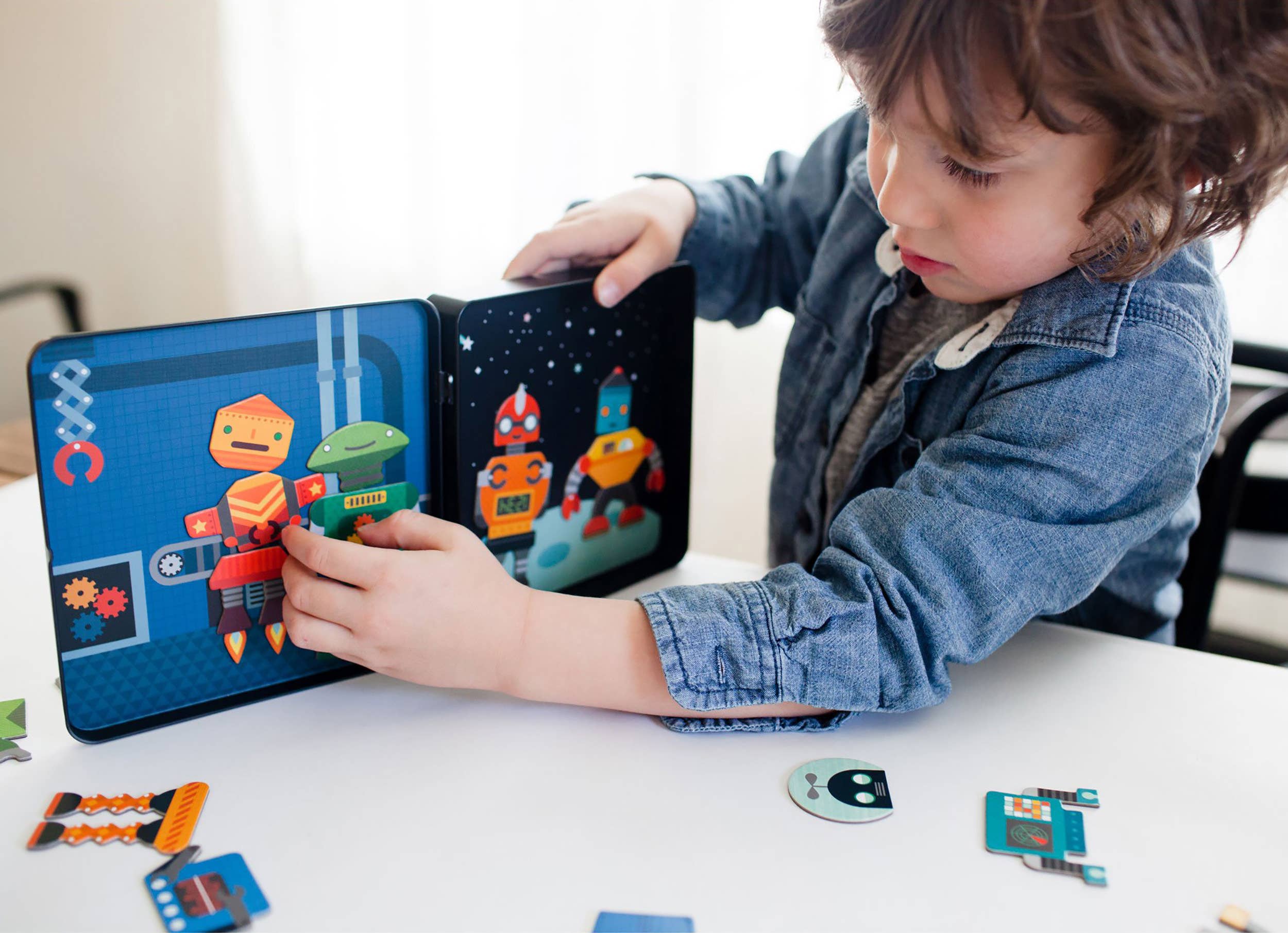 Close up view of a child assembling the magnetic robot pieces inside open tin