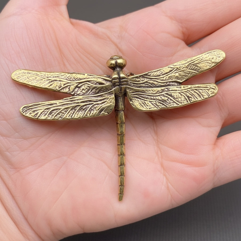 Gold dragonfly-shaped object held in a hand