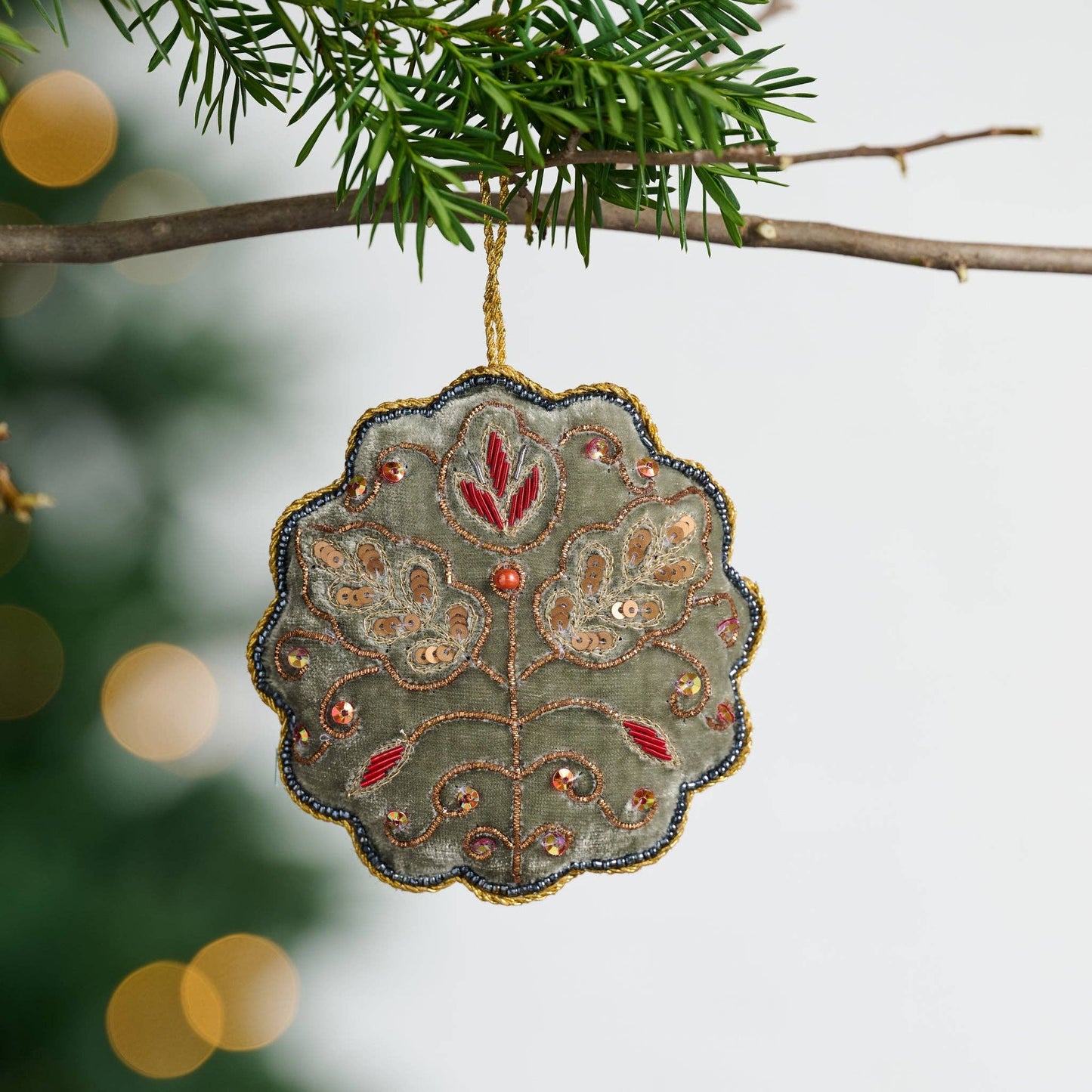 Decorative ornament with floral patterns hanging on a tree branch.