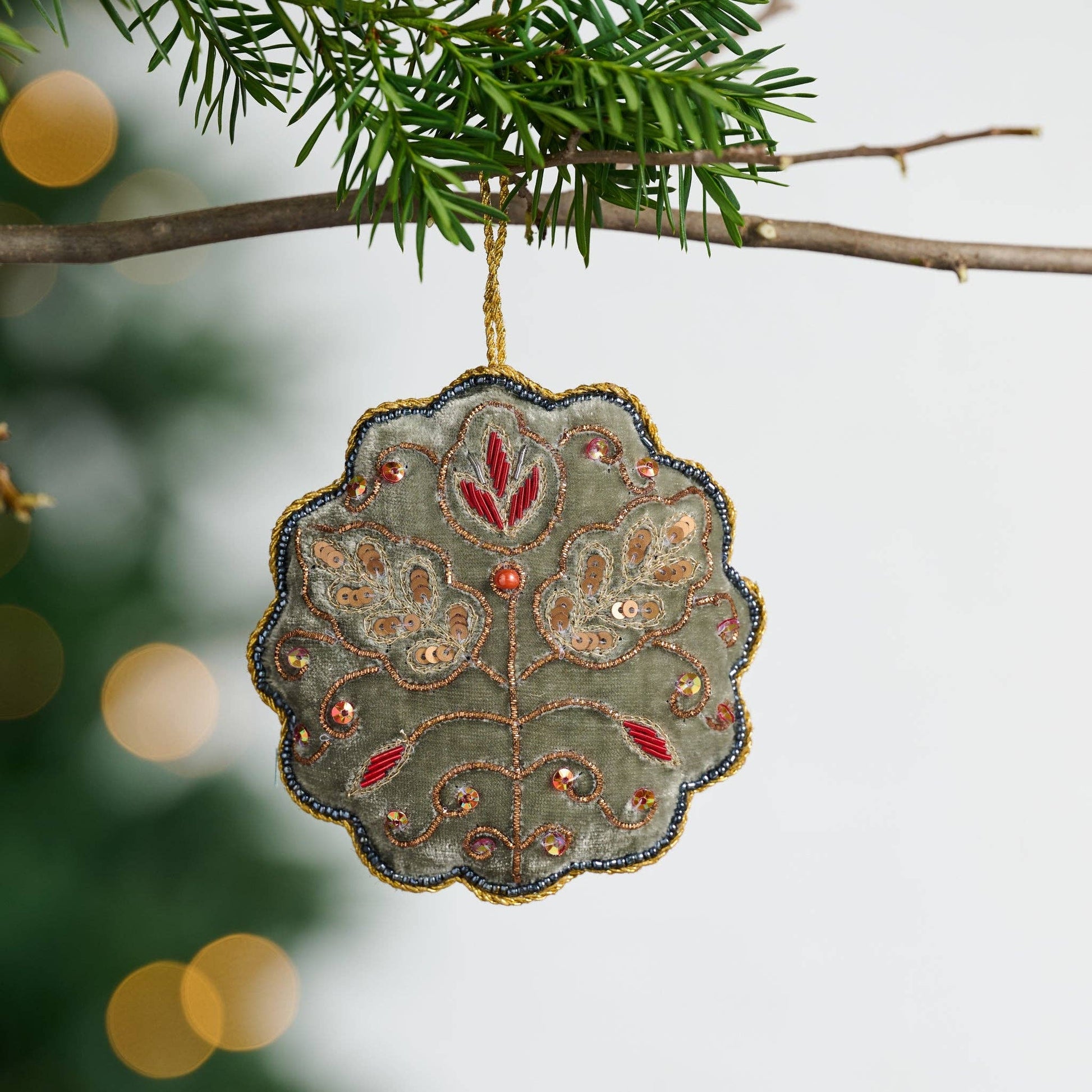 Decorative ornament with floral patterns hanging on a tree branch.