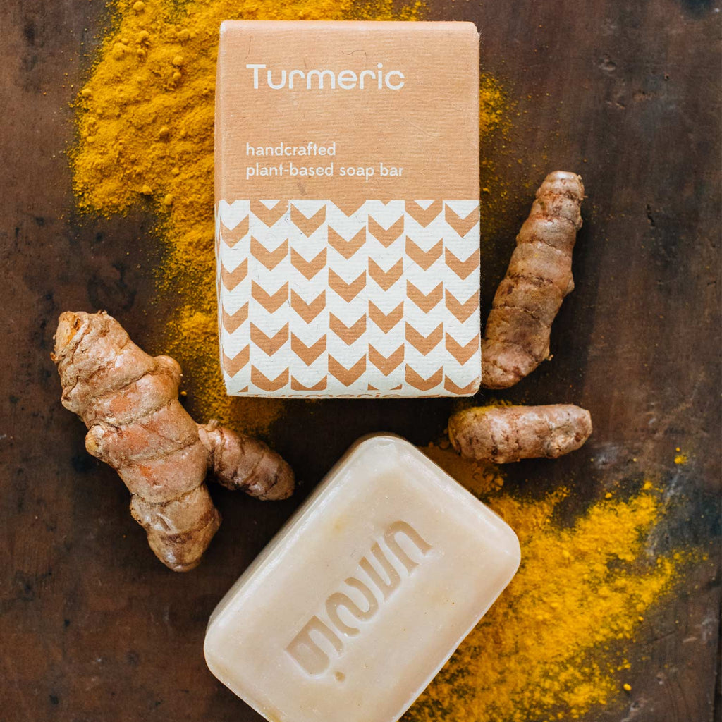 Turmeric soap bar with turmeric powder and roots on a wooden surface