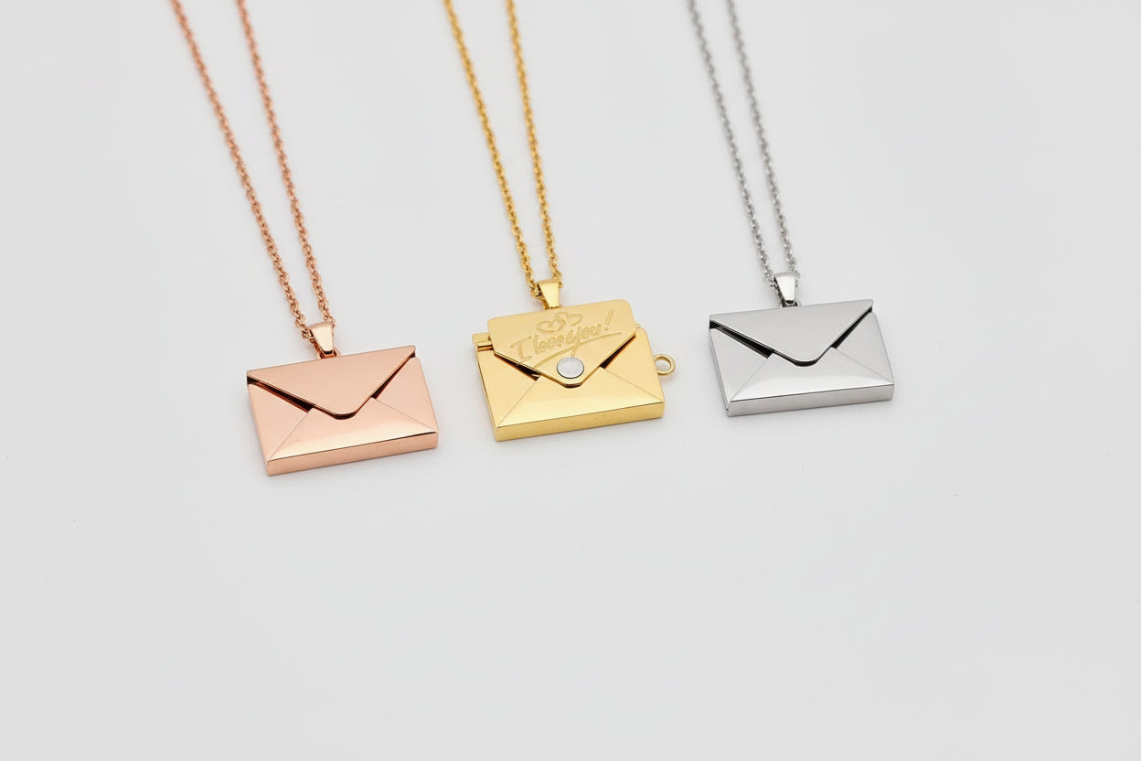 Three gold and silver envelope-shaped pendants on a hand.