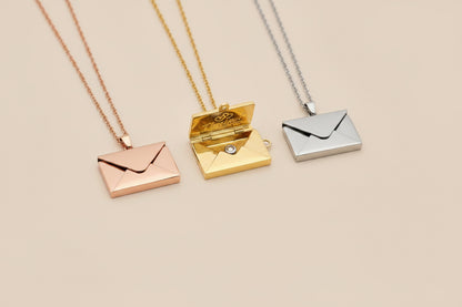 Three gold and silver envelope-shaped pendants on a hand.