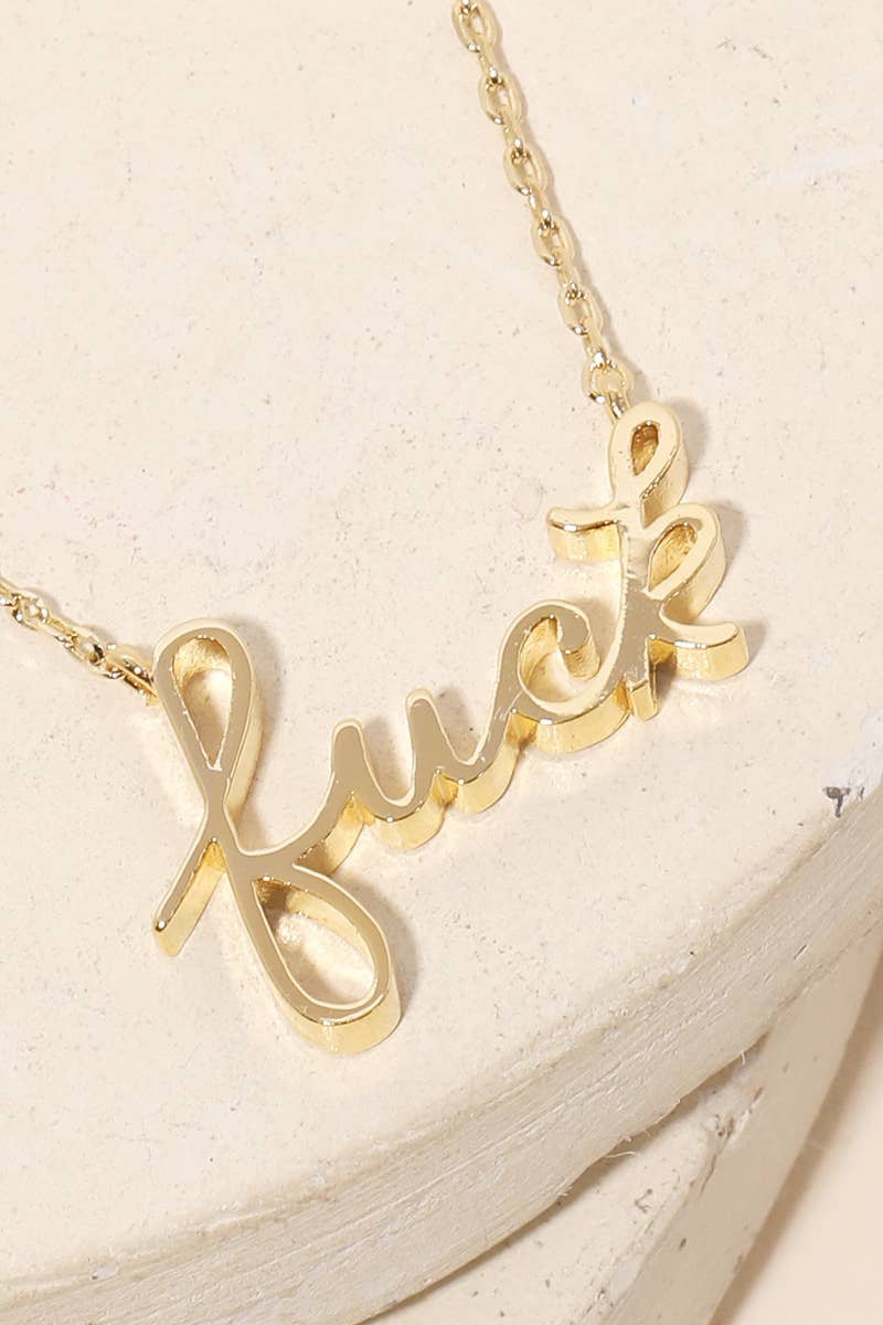 Handwritten “fuck” pendant necklace resting on a minimalist jewelry tray