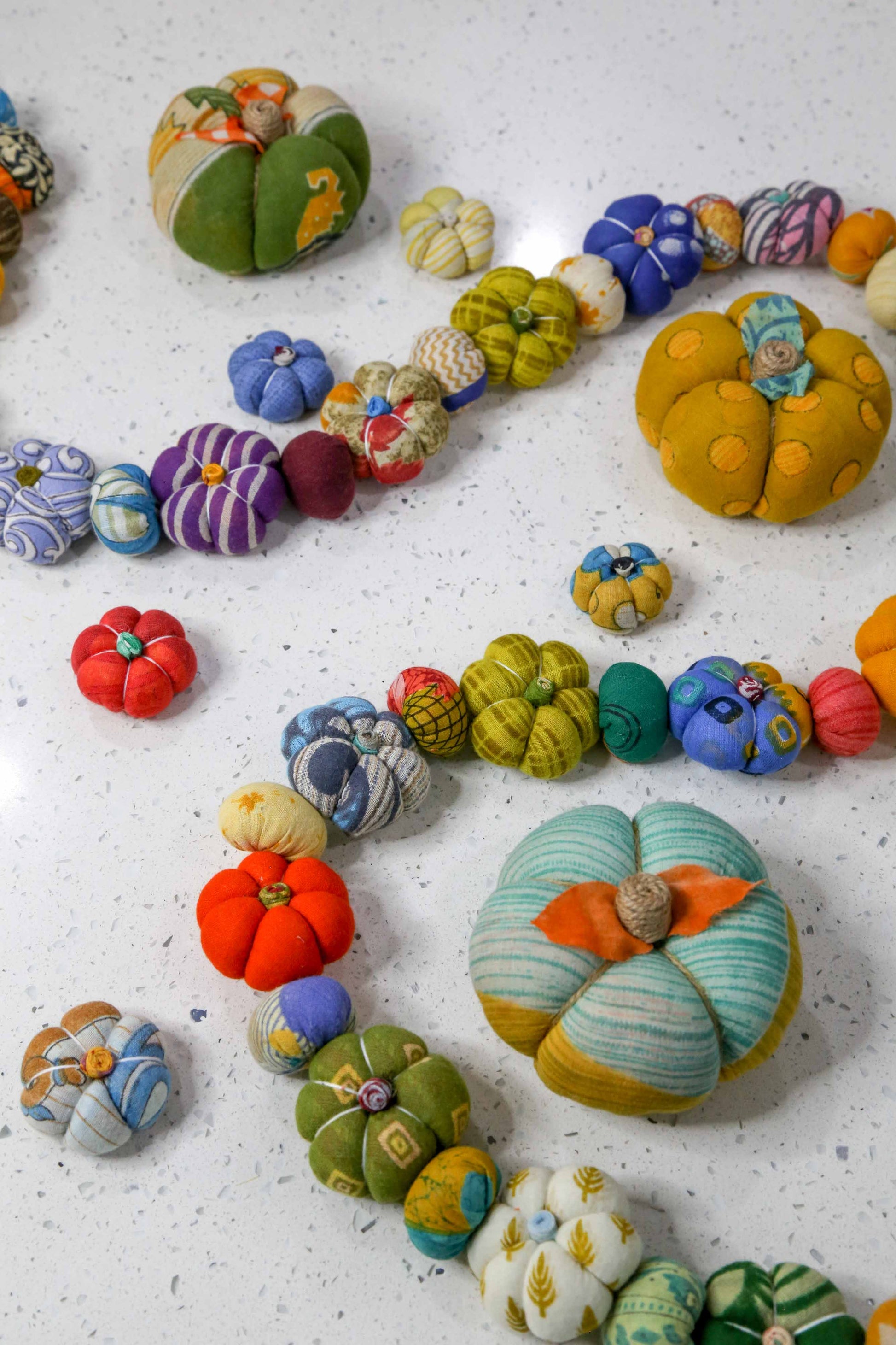 Colorful ceramic pumpkins on a textured white surface