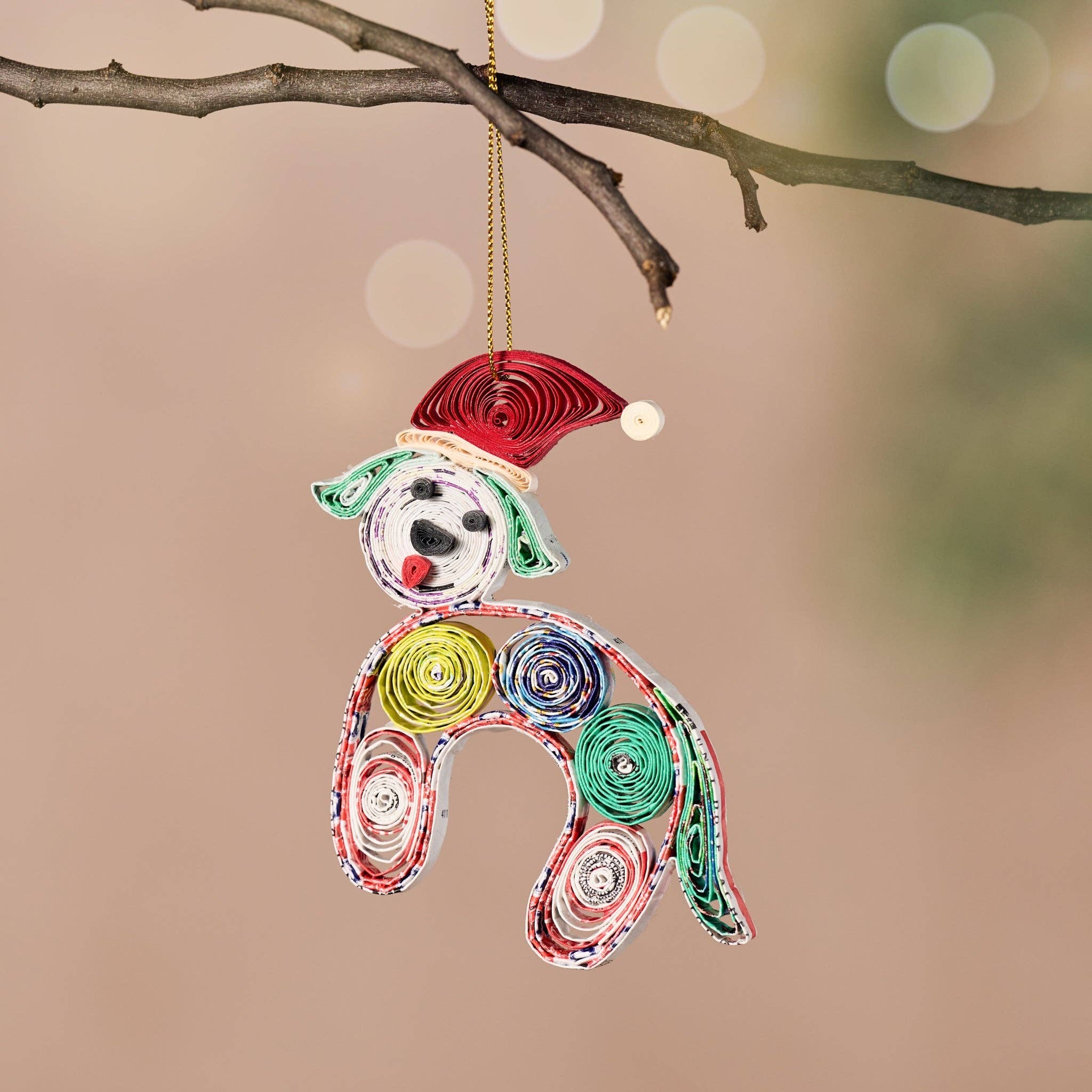 Colorful paper roll dog ornament hanging on a branch with a blurred background