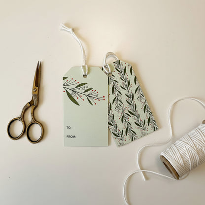 Two gift tags with mistletoe designs on a light background