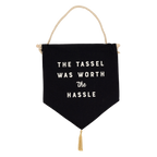 Close up of the Graduation canvas banner with "The Tassle Was Worth the Hassle" text, wood dowel, and gold tassel