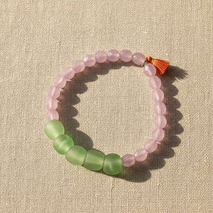 Bracelet with pink and green beads on a beige textured background