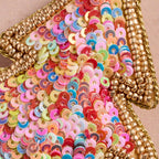 Multicolored sequin ornament with gold trim on a beige background