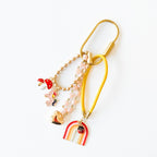 Close up view of the pink themed purse charm with mushrooms, a unicorn, gold filled heart, pink themed rainbow, and an adorable lady bug