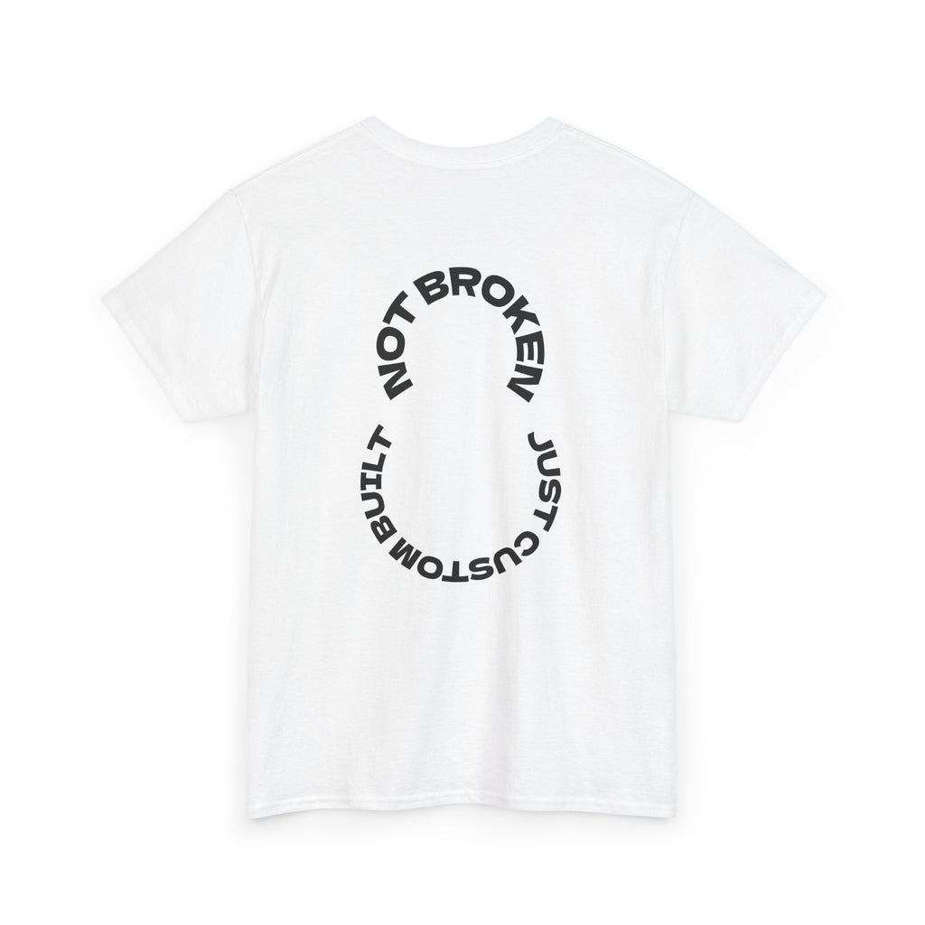 White t-shirt with black text "Not Broken, Just Custom Built" on a white background