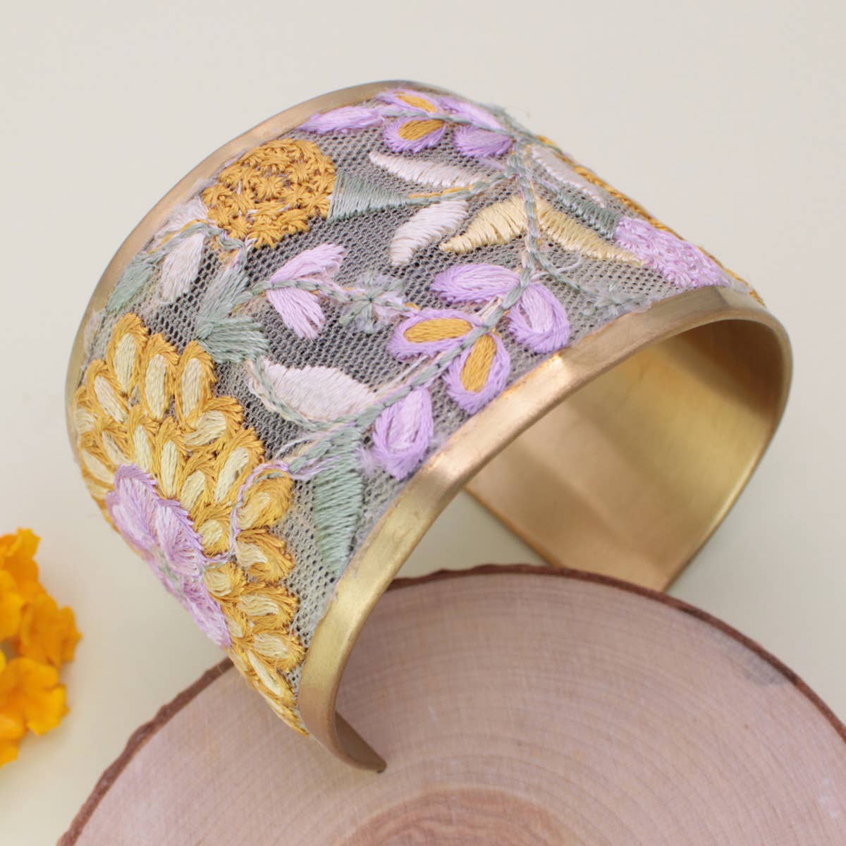 Embroidered cuff bracelet with floral patterns on a wooden surface
