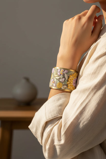 Embroidered cuff bracelet with floral patterns being worn on the wrist against a neutral background