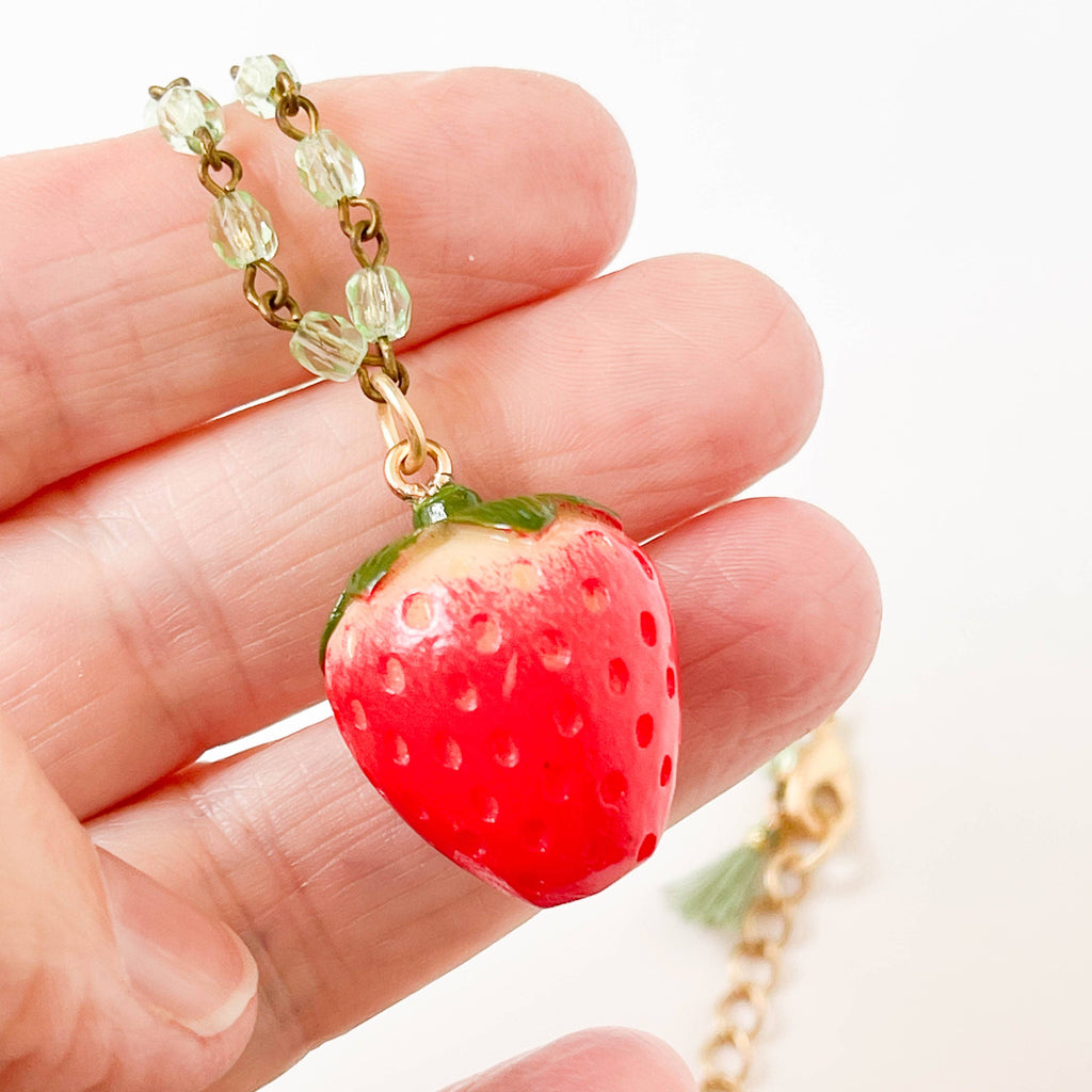 Close up view of the strawberry necklace held in hand