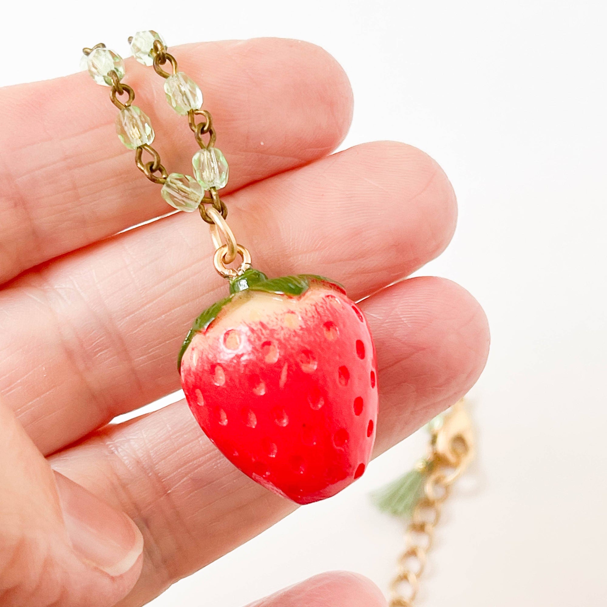 Close up view of the strawberry necklace held in hand